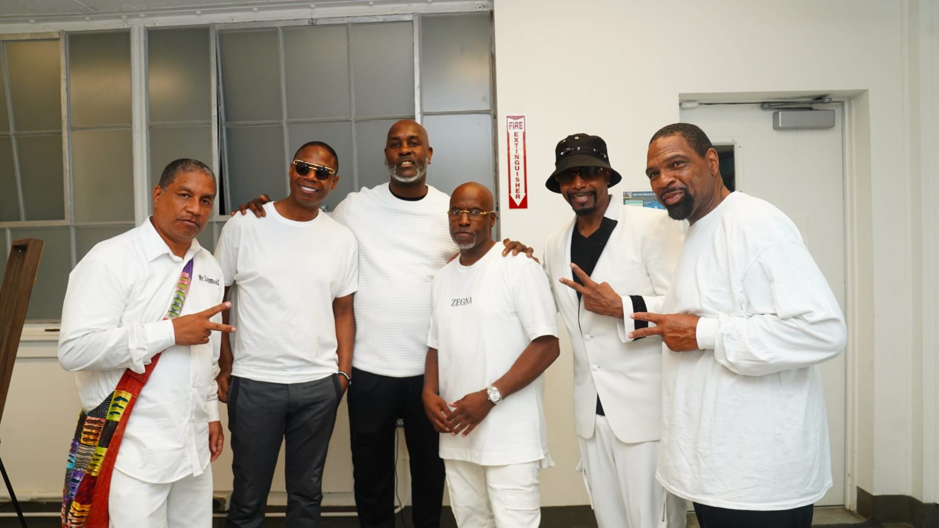 Featured artists and community leaders backstage in all-white attire at a previous Foundation event